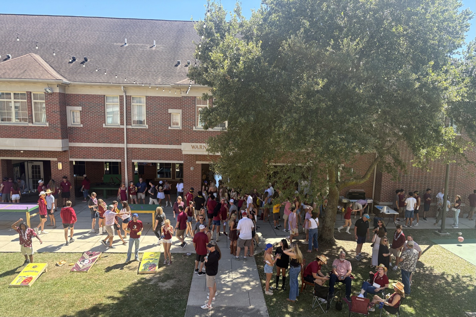 A crowd in garnet and gold gathered in the courtyard outside Warner Peacock Hall for a gameday tailgate, seen from above